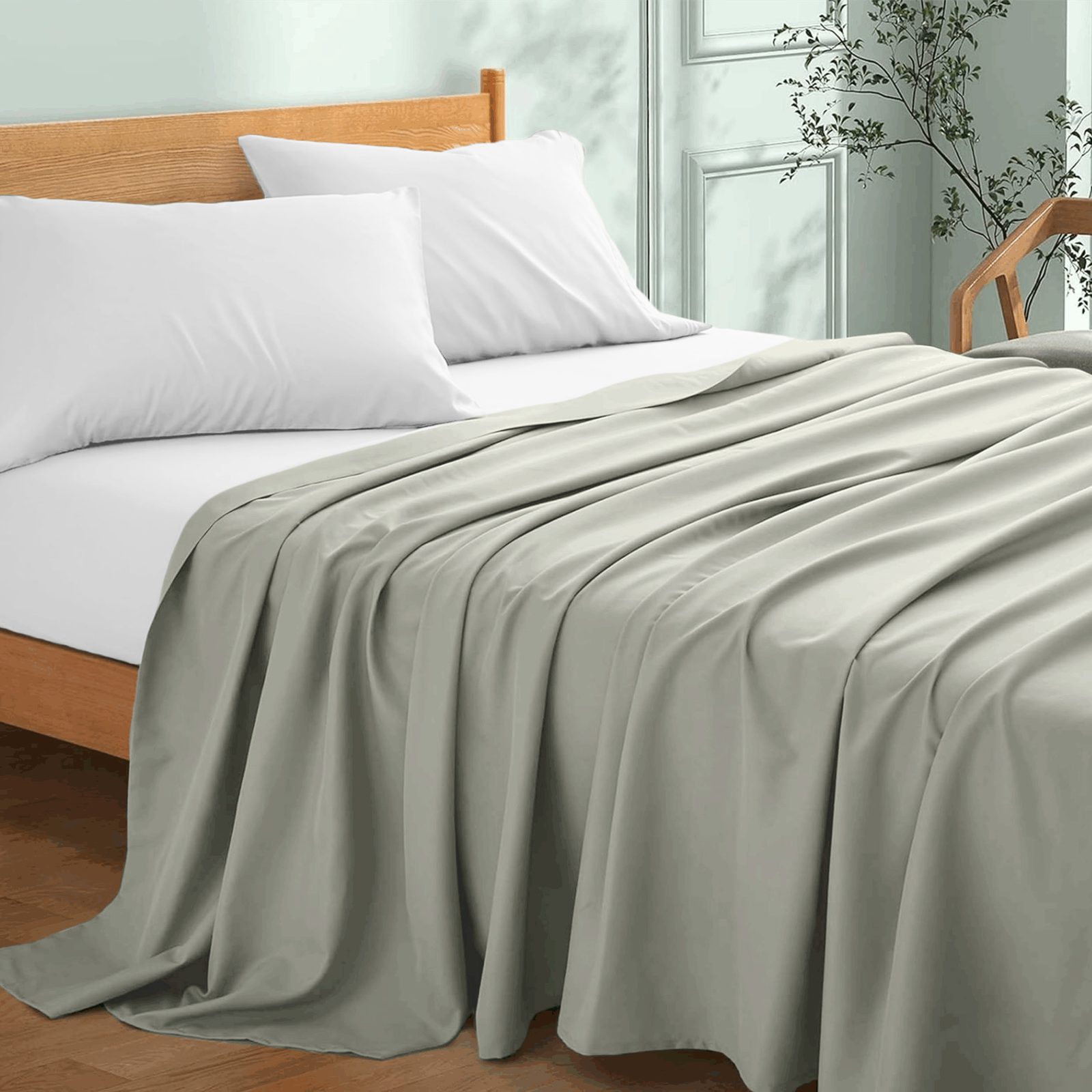 Cama con sábana plana gris claro y almohadas blancas
