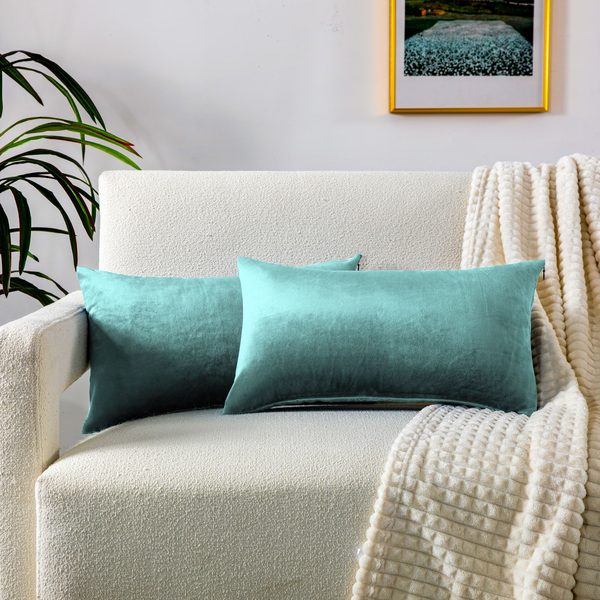 Cojines alargados de terciopelo verde claro en un sillón blanco