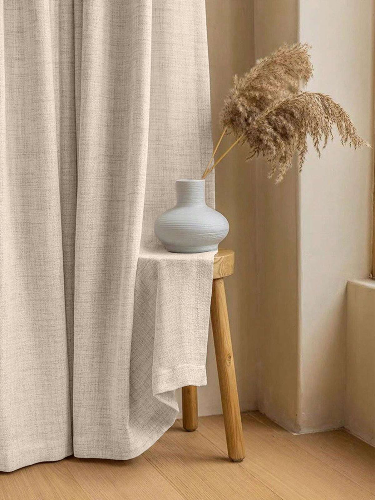 Cortina beige con efecto lino junto a un banco de madera con un jarrón